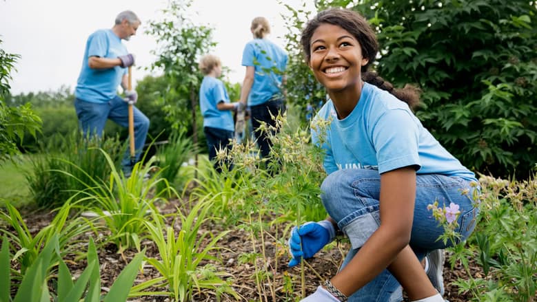 Girl volunteering with a group outside. 